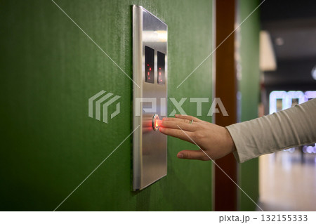 Pressing the elevator button in contemporary high rise buildings signifies modern urban convenience Pressing the elevator button in contemporary high rise buildings signifies modern urban convenience 132155333