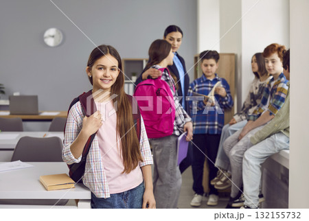 Portrait of happy girl elementary student standing with backpack 132155732