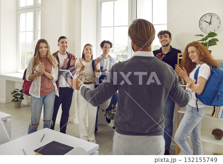 Group of happy students applauding to their teacher or lecturer at the university classroom. 132155749