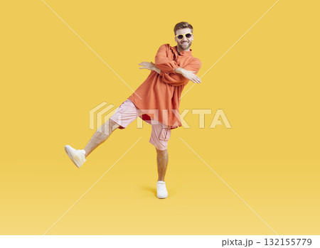 Funny young guy in summer casual clothes having fun dancing isolated on yellow background. Funny young guy in summer casual clothes having fun dancing isolated on yellow background. 132155779