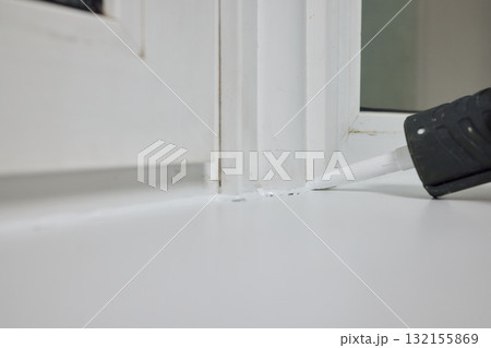 Sealing the corners of windows with caulk for achieving a perfectly neat and polished finish Sealing the corners of windows with caulk for achieving a perfectly neat and polished finish 132155869