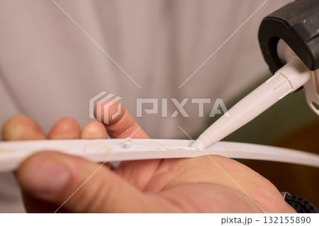 Hand Applying Adhesive with a Caulking Gun for Various Home Interior and Exterior Projects 132155890