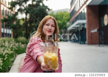 Curvy woman offering from bag of chips. 132155933