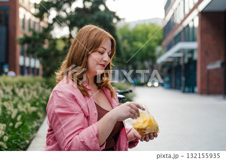 Plus size woman holding potato chip. 132155935
