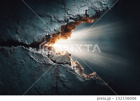 Cracked wall showing bright light emerging from darkness 132156006