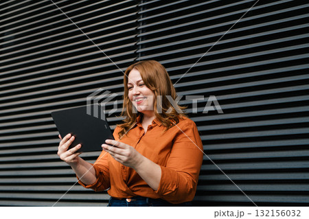 Plus size woman holding tablet, black background. 132156032