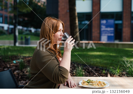 Plus size woman drinking soft soda drink with her lunch. 132156049