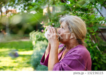 Quiet morning in garden for older woman. Self ritual with coffee. 132156115