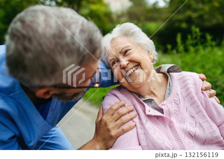 Senior patient and male nurse talking during walk outdoors. Senior patient and male nurse talking during walk outdoors. 132156119