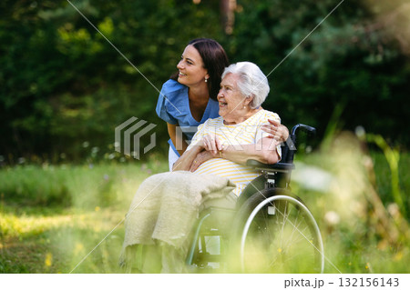Home nurse taking care of elderly woman in wheelchair. 132156143