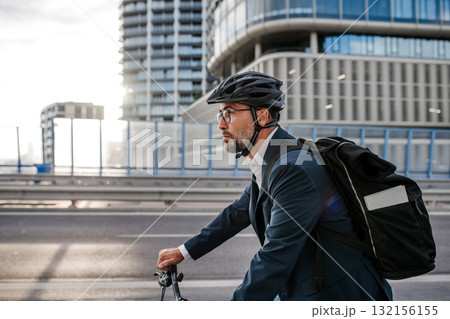 Man riding bike to work in city with helmet and backpack Man riding bike to work in city with helmet and backpack 132156155