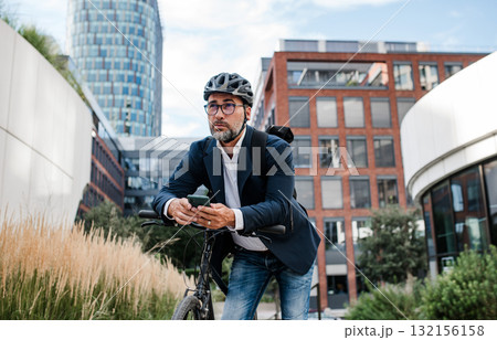 City commuter riding bike from work, reading text message on phone. City commuter riding bike from work, reading text message on phone. 132156158