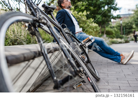Man sitting in urban park with parked bicycle. Man sitting in urban park with parked bicycle. 132156161