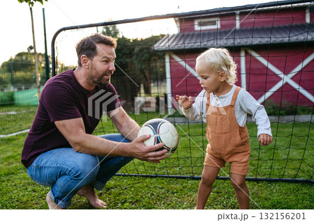 Little boy playing football with father in backyard. Little boy playing football with father in backyard. 132156201