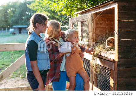 Family visiting rabbits on a sunny farm. Family visiting rabbits on a sunny farm. 132156218