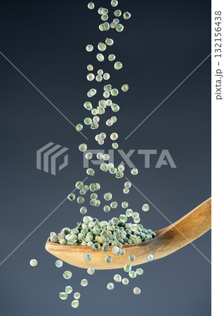 Organic green peppercorns fall from above onto a wooden spoon, ideal for seasoning, cooking and culinary ingredient imagery. Organic green peppercorns fall from above onto a wooden spoon, ideal for seasoning, cooking and culinary ingredient imagery. 132156438