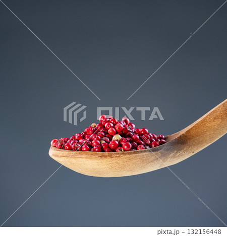 Aromatic dried spice berries displayed on traditional wooden utensil, ideal for gourmet cooking and natural themes Aromatic dried spice berries displayed on traditional wooden utensil, ideal for gourmet cooking and natural themes 132156448