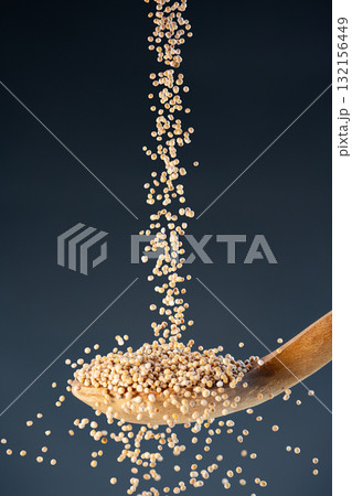 Dried whole Mustrad seeds fall from above onto a wooden spoon, ideal for cooking ingredients and organic food photography 132156449