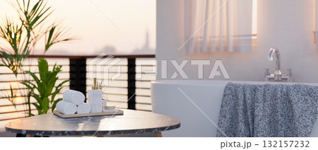 White ceramic bathtub and a grey marble table with towels and shower gel in an outdoor bathroom. White ceramic bathtub and a grey marble table with towels and shower gel in an outdoor bathroom. 132157232