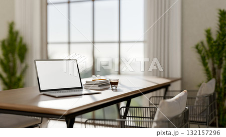 White screen laptop with books and coffee on table and steel armchairs in dining hall of restaurant. 132157296