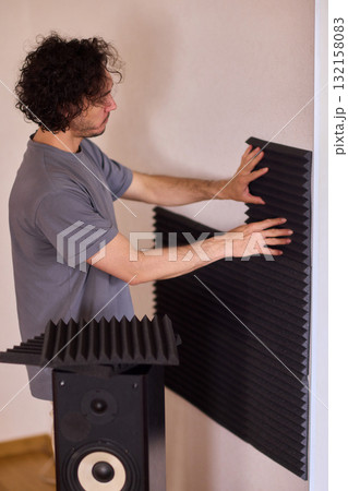 Setting up audio equipment with soundproofing panels in a modern studio environment 132158083