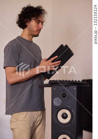 Setting up audio equipment with soundproofing panels in a modern studio environment Setting up audio equipment with soundproofing panels in a modern studio environment 132158124