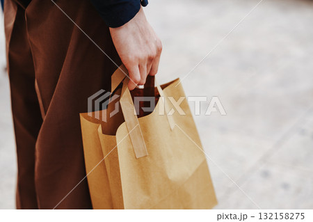Person carrying a brown paper bag while walking on a city street at daytime 132158275