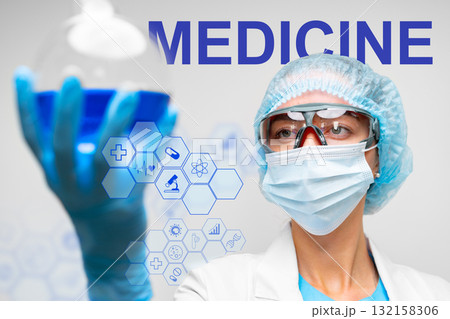 Scientist conducts research in laboratory while holding a blue liquid in a glass container 132158306