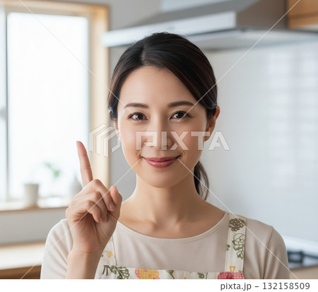 笑顔で人差し指を立てる若い主婦 132158509