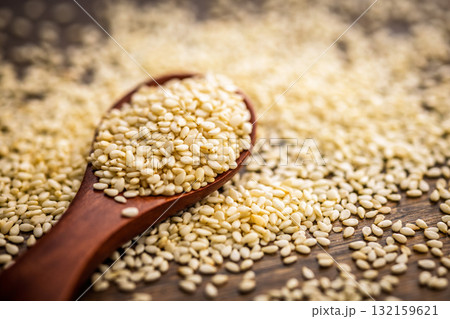 Roasted sesame seeds on spoon on wooden table. 132159621