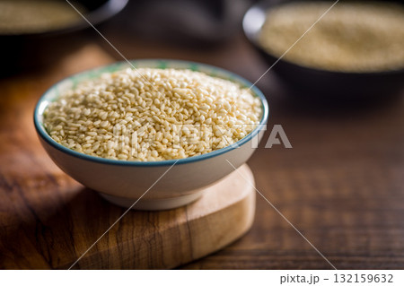 Roasted sesame seeds in bowl on wooden table. 132159632