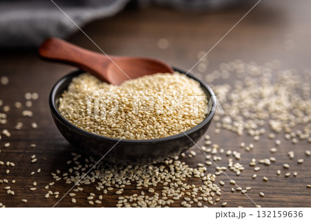 Roasted sesame seeds in bowl on wooden table. 132159636