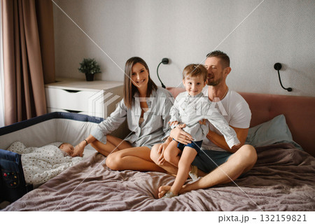 Smiling Family With Toddler And Newborn In Cozy Bedroom Smiling Family With Toddler And Newborn In Cozy Bedroom 132159821