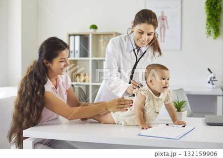 Pediatrician and mother holding baby during clinic checkup, stethoscope assessment 132159906