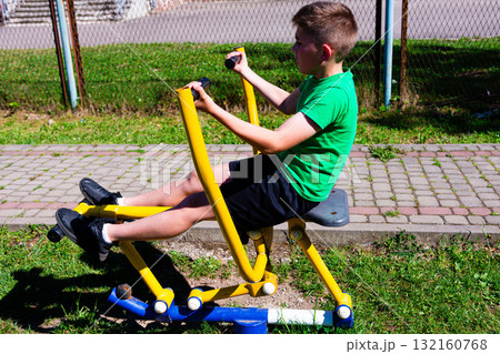 Boy exercising on outdoor fitness equipment. Healthy lifestyle, active kid. Boy exercising on outdoor fitness equipment. Healthy lifestyle, active kid. 132160768