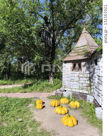 Eerie Halloween Display Stone Cottage, Pumpkins, Ghoulish Figure Among Verdant Trees Eerie Halloween Display Stone Cottage, Pumpkins, Ghoulish Figure Among Verdant Trees 132161021