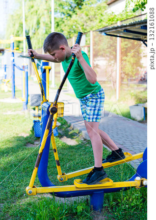 Boy exercising on outdoor fitness equipment. Healthy lifestyle and outdoor fun. Boy exercising on outdoor fitness equipment. Healthy lifestyle and outdoor fun. 132161088