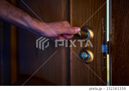 A hand is positioned on the door knob, fully prepared to open the entrance with ease A hand is positioned on the door knob, fully prepared to open the entrance with ease 132161330