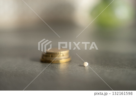 Close-up of a baby tooth lying in front of a stack of coins. Concept of tooth fairy tradition, childhood milestones and symbolic rewards. 132161598