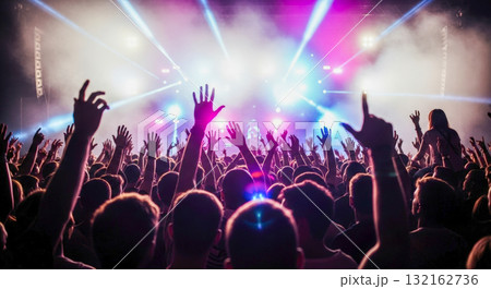 Crowd of people with hands raised at music concert or festival, enjoying live show with stage lights and smoke, party and entertainment concept 132162736