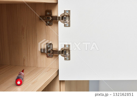 Modern and adjustable silver cabinet door hinges for furniture , with visible screws and hinge mechanism, close-up Modern and adjustable silver cabinet door hinges for furniture , with visible screws and hinge mechanism, close-up 132162851