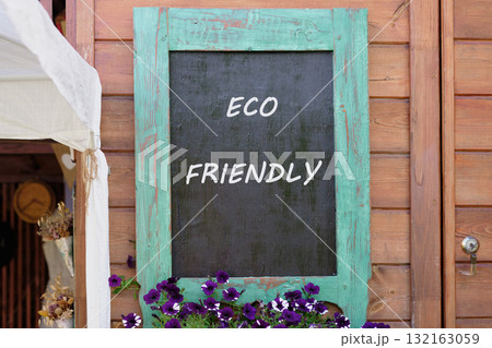 A colorful wooden board highlights the eco friendly message, surrounded by blooming purple flowers 132163059