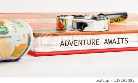 On a vibrant desk, a book titled Adventure Awaits invites exploration, accompanied by a magnifying glass and rolled cash, suggesting exciting travel opportunities and daring experiences On a vibrant desk, a book titled Adventure Awaits invites exploration, accompanied by a magnifying glass and rolled cash, suggesting exciting travel opportunities and daring experiences 132163085