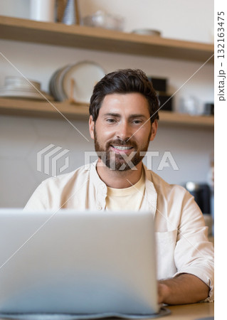 Bearded man working on his laptop in the kitchen Bearded man working on his laptop in the kitchen 132163475