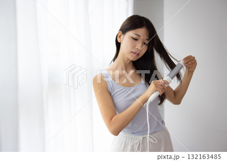 ヘアアイロンをかける若い女性 132163485
