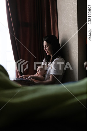 Mother and Baby Using Laptop by Window Mother and Baby Using Laptop by Window 132163608