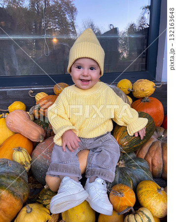 Baby in Yellow Sweater Sitting on Pumpkins Baby in Yellow Sweater Sitting on Pumpkins 132163648