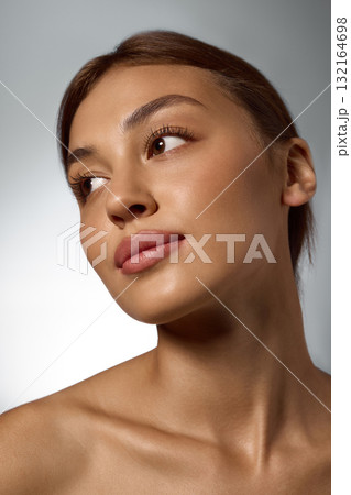 Close-up of woman with natural glowing skin showing serene confidence and healthy beauty 132164698