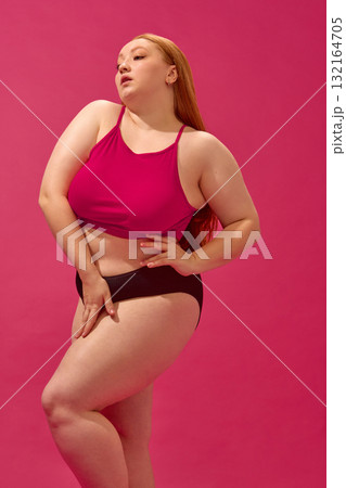 Plus-size model in pink top and black bottoms showing natural confidence and style 132164705