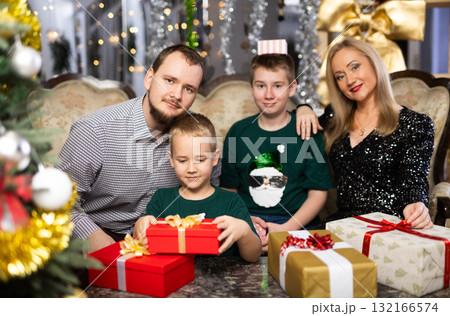 Smiling family celebrating Christmas and giving each other gifts 132166574